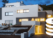 Modernes Einfamilienhaus mit Münzsymbolen als Darstellung der Kosten eines KNX-Smart-Homes
